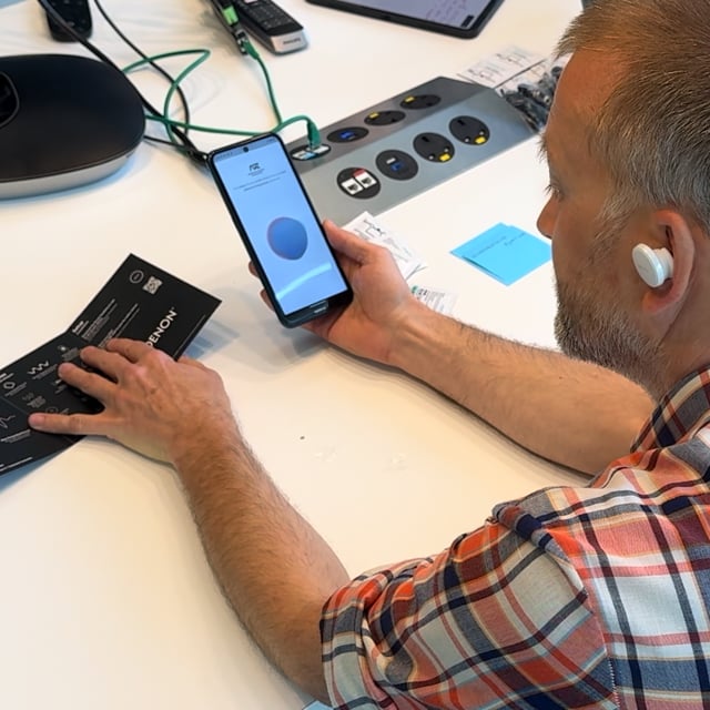 A participant wearing one earbud, watching the profile-creation orb on the phone screen.